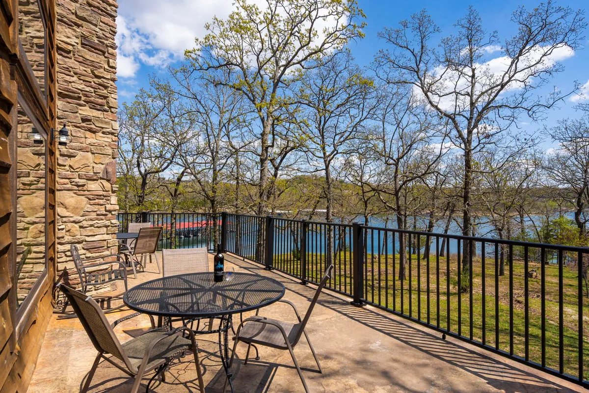 An exterior shot of a patio table set against the backdrop of the lake, surrounded by trees. The tranquil setting invites guests to dine outdoors, relax, or simply enjoy the lakeside scenery just steps from the porch.